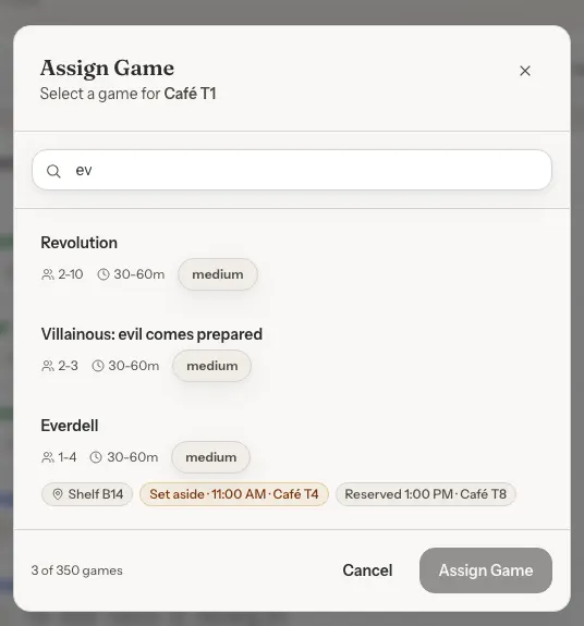 The Assign Game window. Everdell shows Shelf B14, Set aside 11:00 AM Café T4 and Reserved 1:00 PM Café T8 labels.